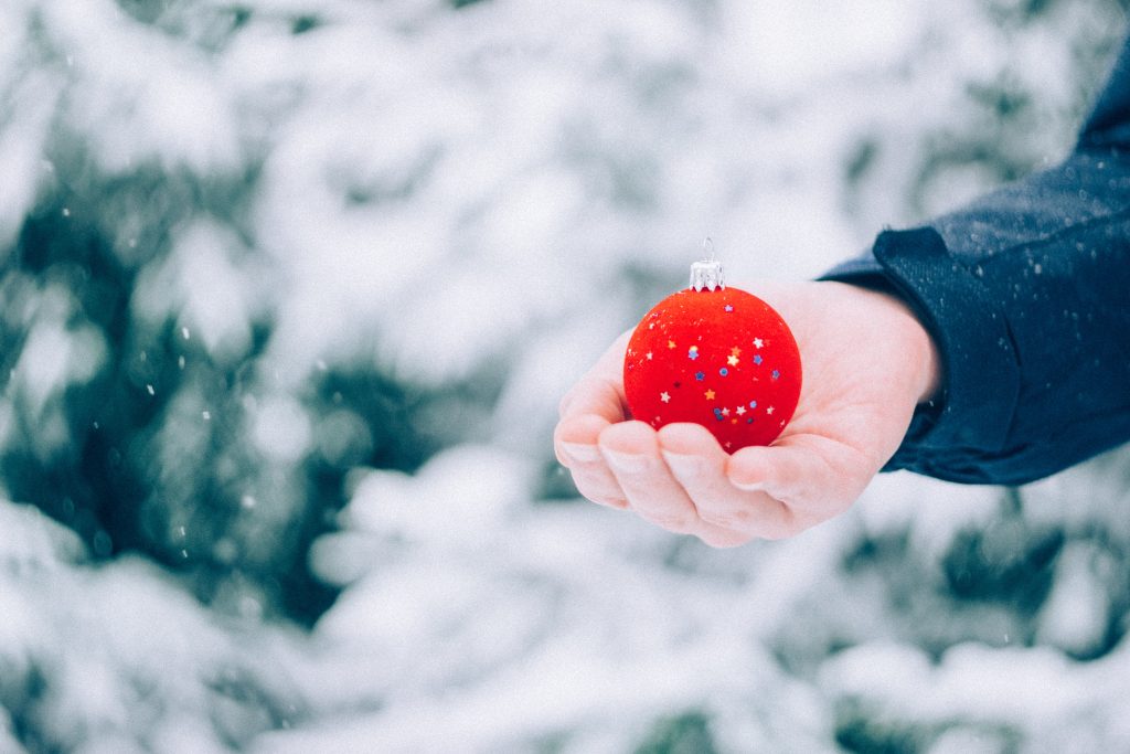 Holiday budget man holding red ornament