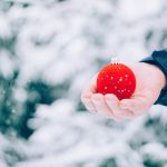 Holiday budget man holding red ornament