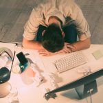 An overworked man laying his head on his desk